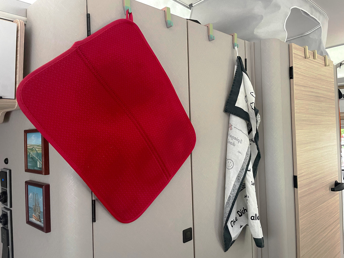 Der Aufsteckhaken für Schrank- und Badtüren im Eriba Touring, Troll oder Puck in der Version "Harlekin". Hier ist ein Nutzungsbeispiel zu sehen, bei dem je Schanktür 2 Haken "Harlekin" aufgesteckt sind - einmal mit einem Geschirrhandtuch und einmal mit einer Geschirrunterlage.
