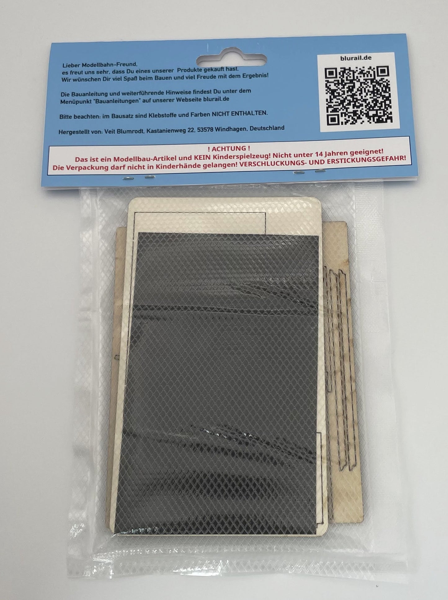Beispielfoto eines Bausatzes des Wartehauses Haltepunkt "Unterneudorf" in Spur H0, hier in seiner Verpackung mit Folietüte und Produktlabel. Gezeigt wird die Rückseite des verpackten Produktes.