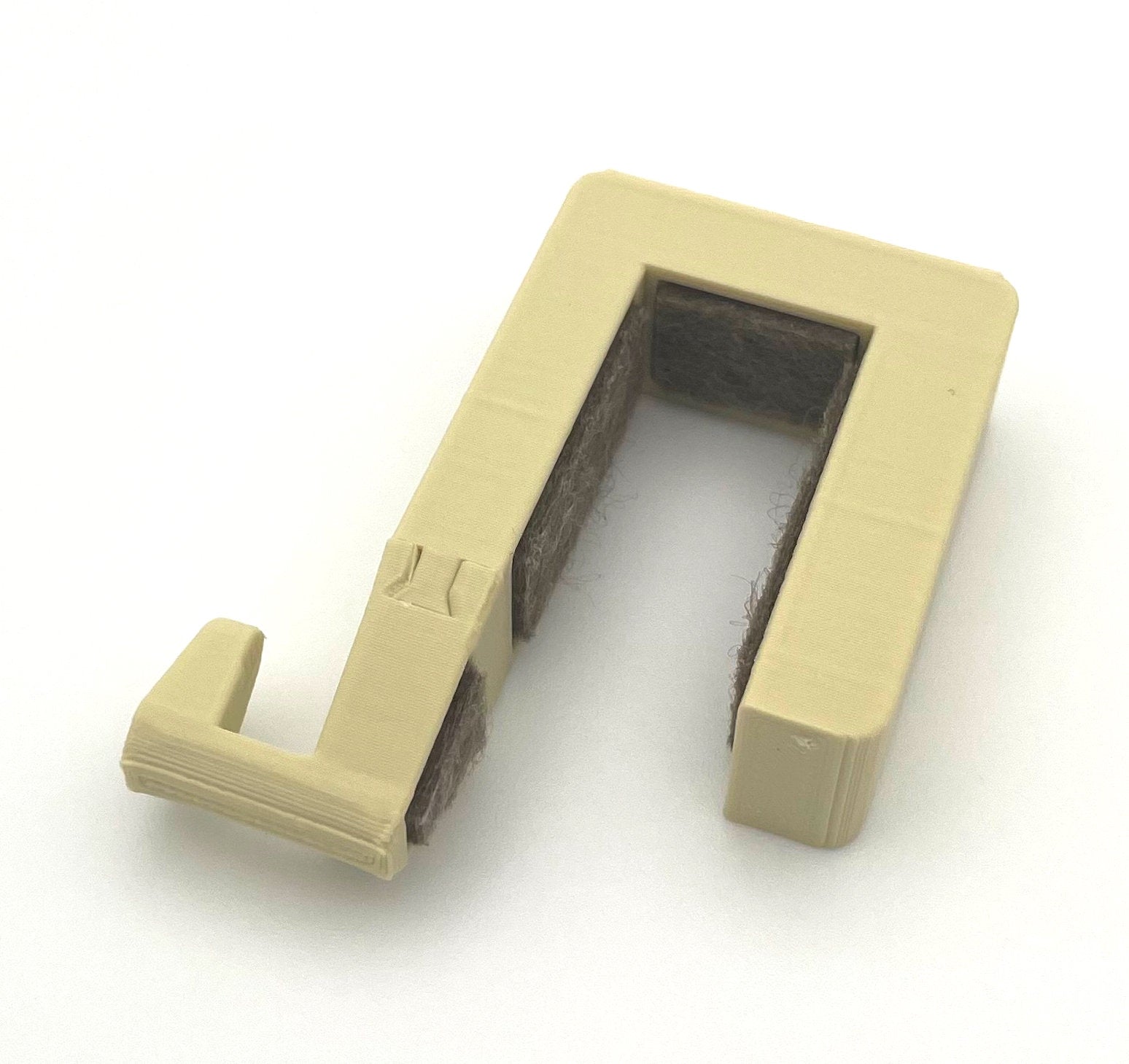 Gesamtansicht des Aufsteckhakens für Schrank- und Badtüren im Eriba Touring, Troll oder Puck.
Zu sehen ist die beige Variante. Gut zu erkennen ist die Filzeinlage, die das Holzdekor der Türen von Kratzern schützen soll. 